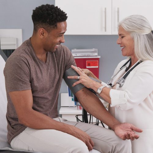 Mature white female physician checking male patients blood pressure at clinic